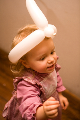 Portrait fille de 2 ans coiffée d'une sculpture de ballons au cours d'une animation d'anniversaire.