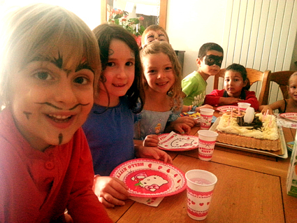 Enfants maquillés à table autour du goûter d'anniversaire.